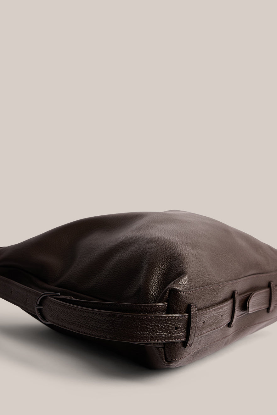Brown leather bag with a strap on a beige background